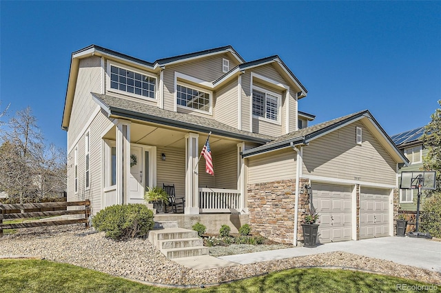 view of front of property featuring an attached garage, a porch, driveway, and stone siding