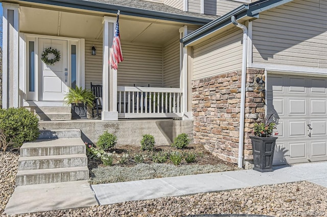entrance to property with a porch, roof with shingles, an attached garage, and stone siding