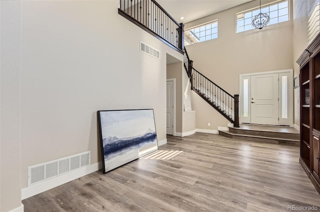 entryway with visible vents, baseboards, a high ceiling, and wood finished floors