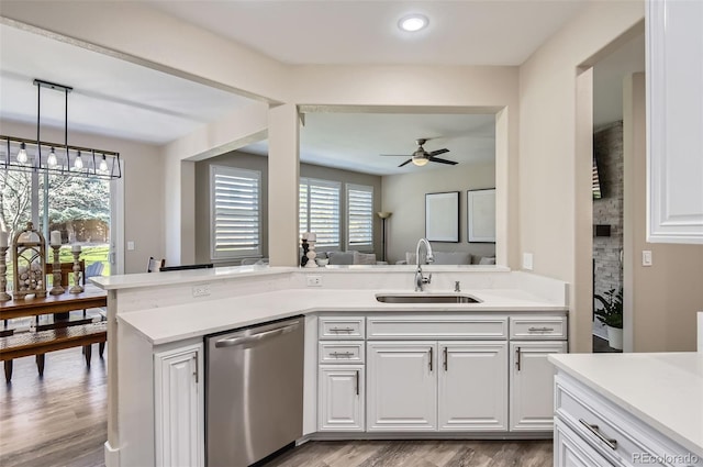 kitchen featuring stainless steel dishwasher, a ceiling fan, light wood-type flooring, light countertops, and a sink
