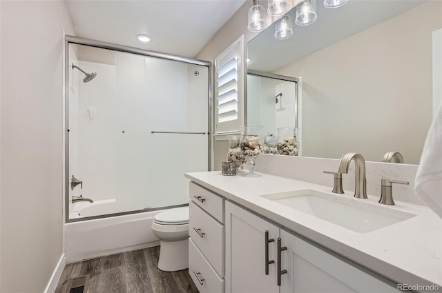 full bath featuring visible vents, wood finished floors, vanity, combined bath / shower with glass door, and toilet