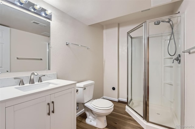 bathroom with toilet, a shower stall, wood finished floors, and vanity