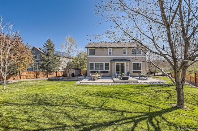 back of property featuring a storage unit, a fenced backyard, a patio area, a yard, and a fire pit