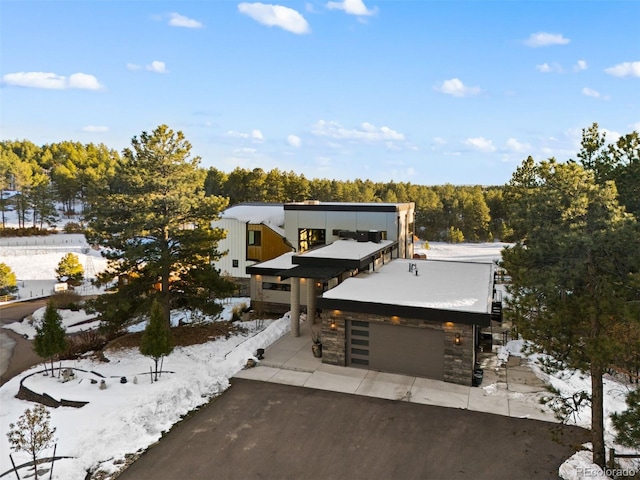 view of front of home featuring aphalt driveway, stone siding, and a garage