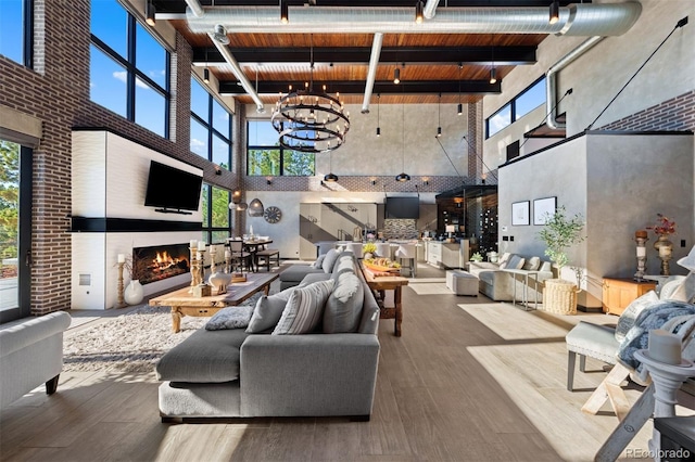 living area featuring a wealth of natural light, wood finished floors, a lit fireplace, and an inviting chandelier