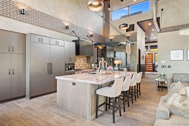 kitchen featuring visible vents, a towering ceiling, modern cabinets, light stone counters, and a breakfast bar