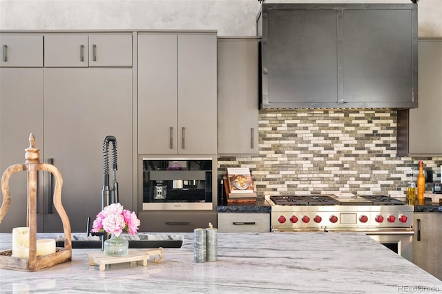 kitchen with stone counters, tasteful backsplash, range with two ovens, and gray cabinetry