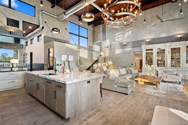 kitchen featuring wooden ceiling, wood finished floors, a sink, a towering ceiling, and open floor plan