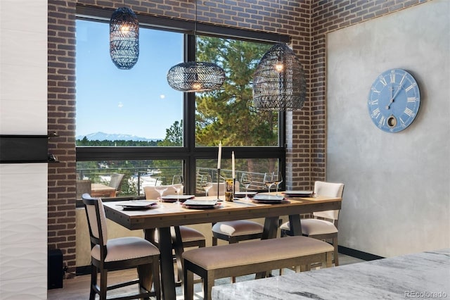 dining area featuring brick wall and wood finished floors