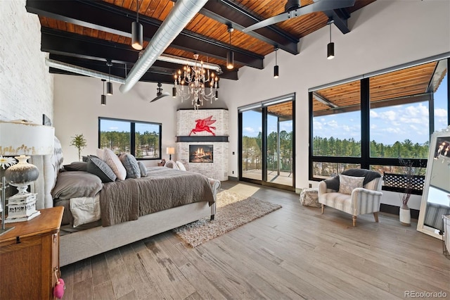 bedroom with wood ceiling, wood finished floors, beamed ceiling, access to exterior, and a lit fireplace