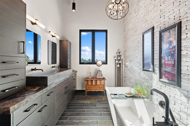 bathroom with a tub to relax in, a wealth of natural light, wood tiled floor, and double vanity