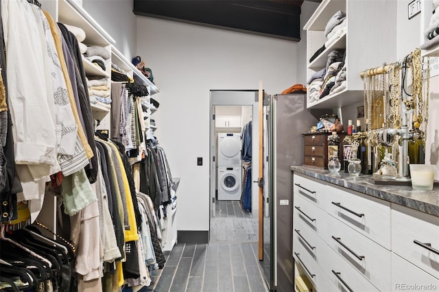 spacious closet with wood finish floors and stacked washer and clothes dryer