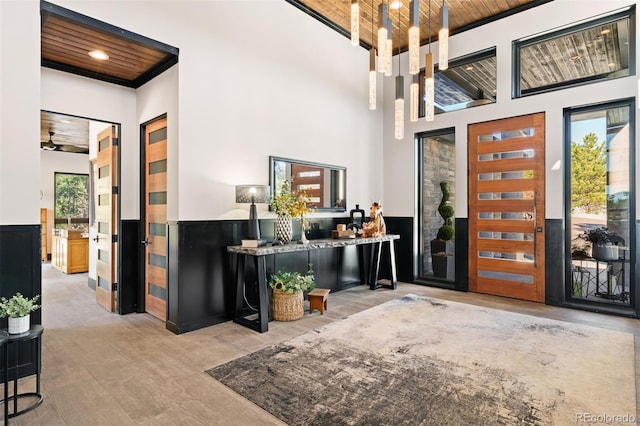 foyer entrance featuring a wainscoted wall, a high ceiling, a chandelier, and wood ceiling