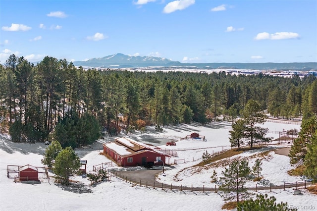 snowy aerial view featuring a forest view and a mountain view