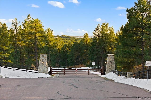 view of gate with a forest view and fence