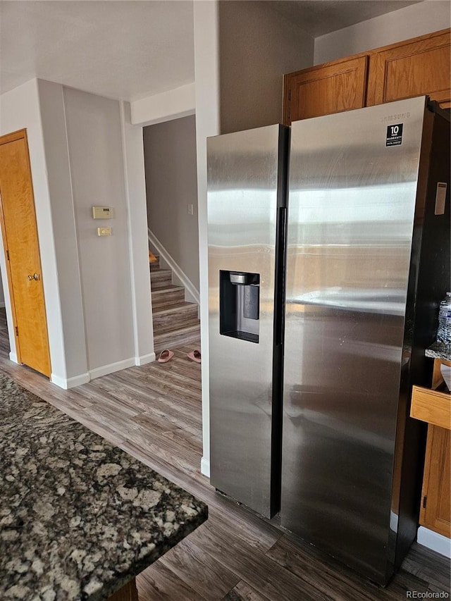 kitchen featuring stainless steel refrigerator with ice dispenser, dark stone counters, and dark hardwood / wood-style flooring