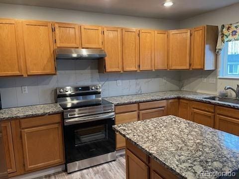 kitchen with stainless steel electric stove, sink, decorative backsplash, light hardwood / wood-style floors, and light stone counters