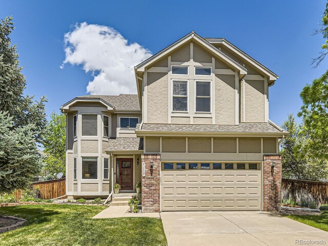 view of front of property featuring stucco siding, an attached garage, driveway, brick siding, and roof with shingles
