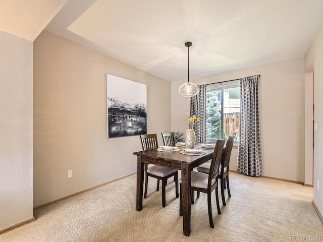 dining area with baseboards and light colored carpet