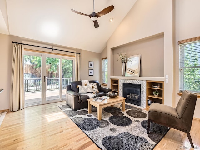 living room with high vaulted ceiling, plenty of natural light, wood finished floors, a ceiling fan, and a fireplace