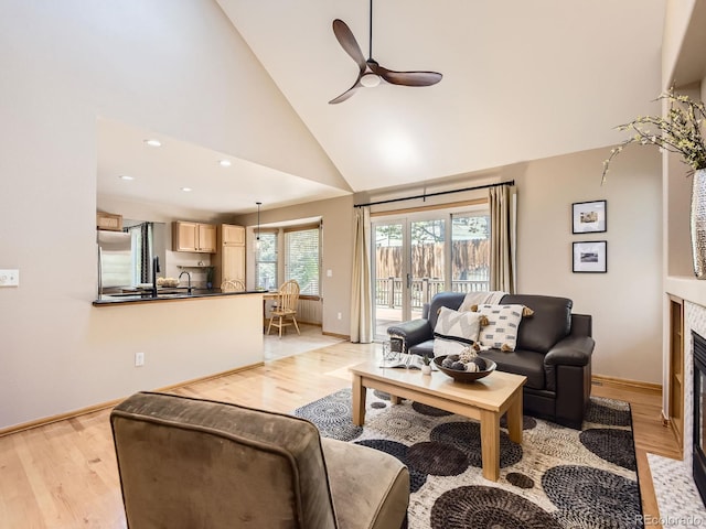 living area with high vaulted ceiling, ceiling fan, baseboards, light wood finished floors, and recessed lighting