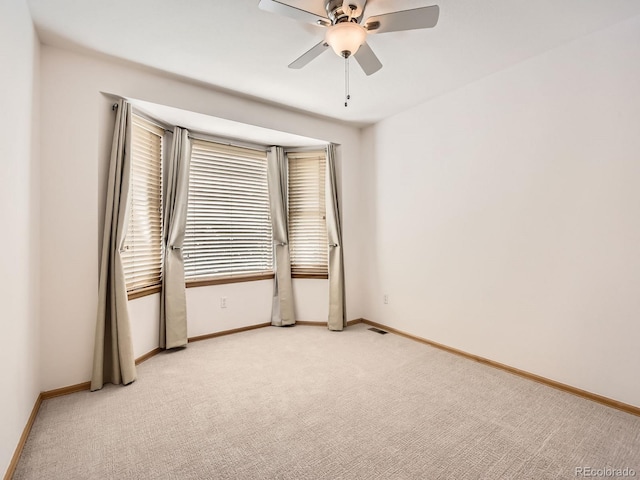 unfurnished room with light colored carpet, baseboards, and ceiling fan