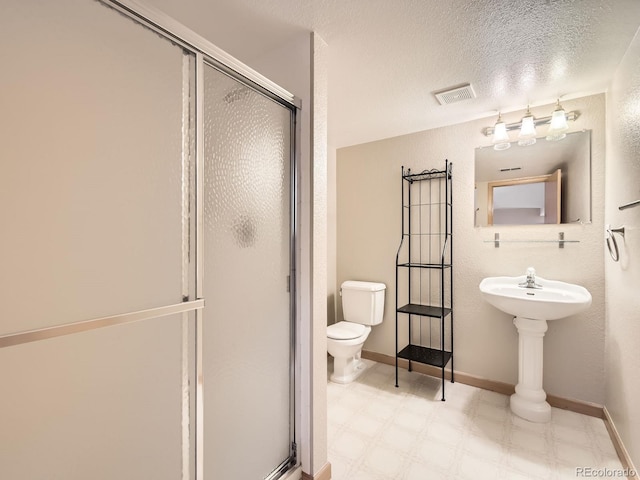 full bathroom with a shower stall, tile patterned floors, toilet, baseboards, and a textured ceiling