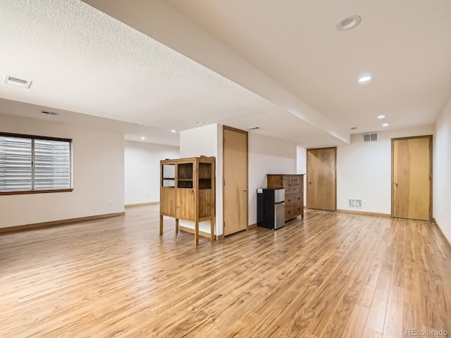unfurnished living room with light wood-type flooring, recessed lighting, and baseboards