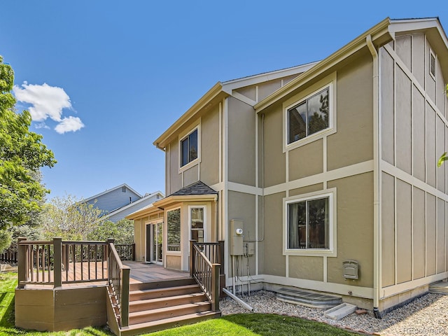 rear view of house featuring board and batten siding, a deck, and a yard