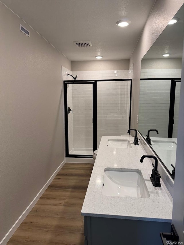 bathroom with an enclosed shower, vanity, wood-type flooring, and toilet