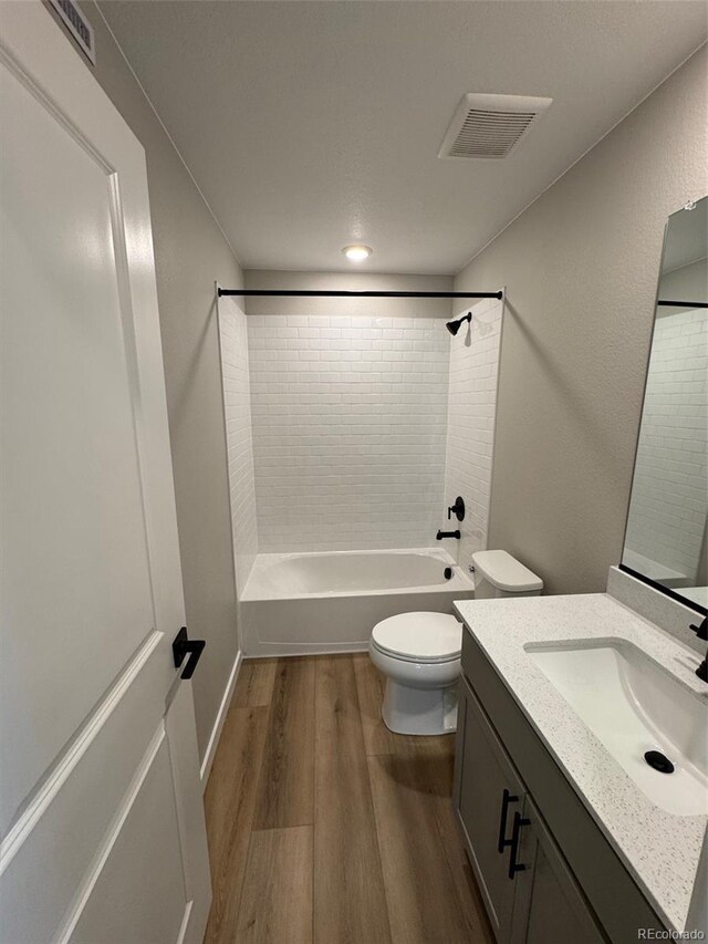 full bathroom featuring tiled shower / bath, wood-type flooring, toilet, and vanity