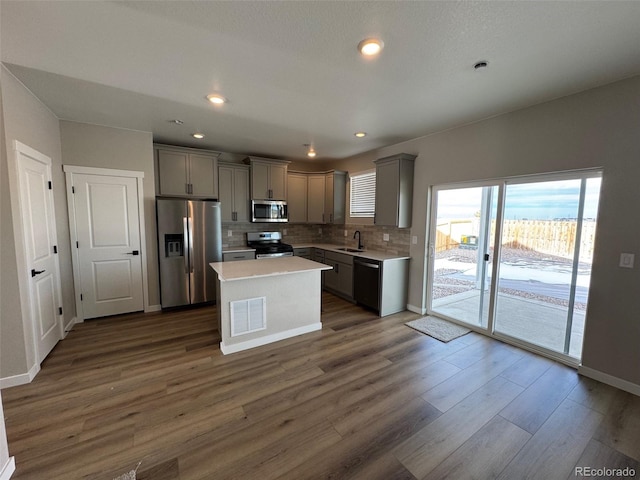 kitchen featuring gray cabinets, a kitchen island, appliances with stainless steel finishes, and dark hardwood / wood-style flooring