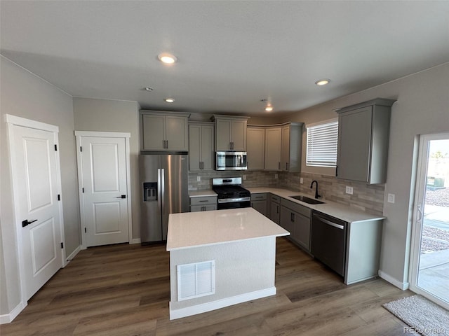 kitchen featuring gray cabinetry, sink, stainless steel appliances, and a center island