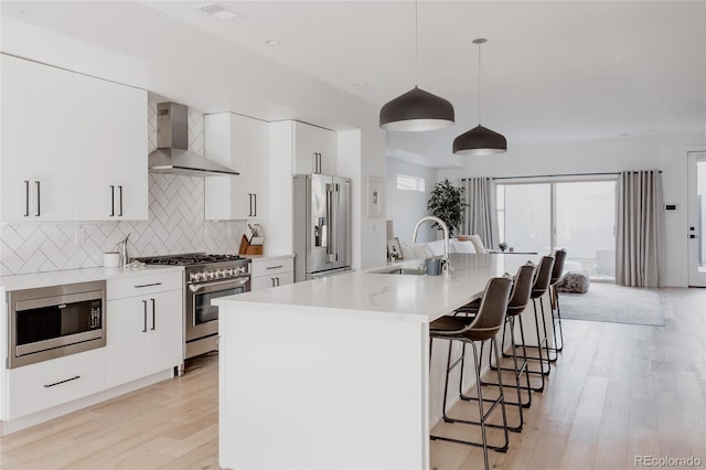 1322 Raleigh St, Denver, CO 80204 - kitchen with premium appliances, a sink, wall chimney range hood, light wood-type flooring, and decorative backsplash