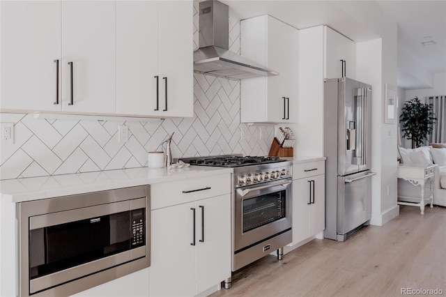 1322 Raleigh St, Denver, CO 80204 - kitchen featuring wall chimney exhaust hood, high end appliances, white cabinetry, backsplash, and light wood-style flooring