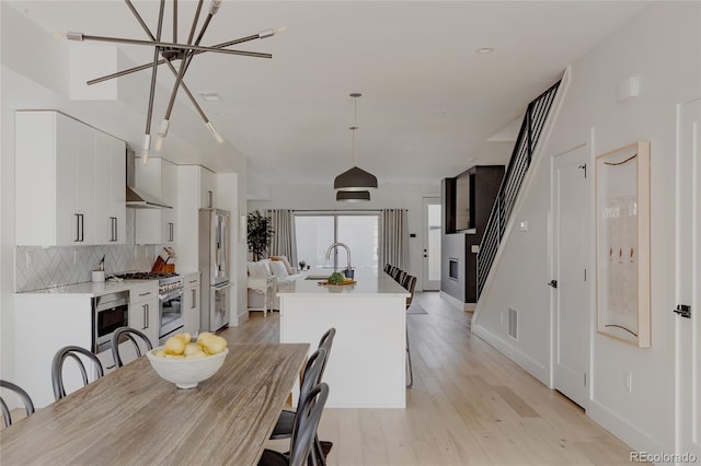 1322 Raleigh St, Denver, CO 80204 - dining area featuring baseboards, a chandelier, stairway, light wood-style flooring, and visible vents