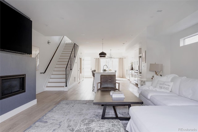 1322 Raleigh St, Denver, CO 80204 - living area with a glass covered fireplace, stairway, baseboards, and light wood finished floors