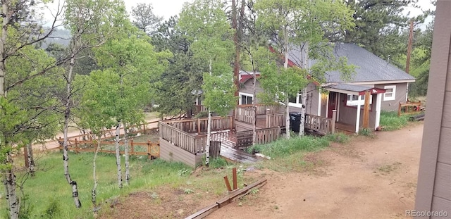 exterior space with a shingled roof, a deck, and an outdoor structure