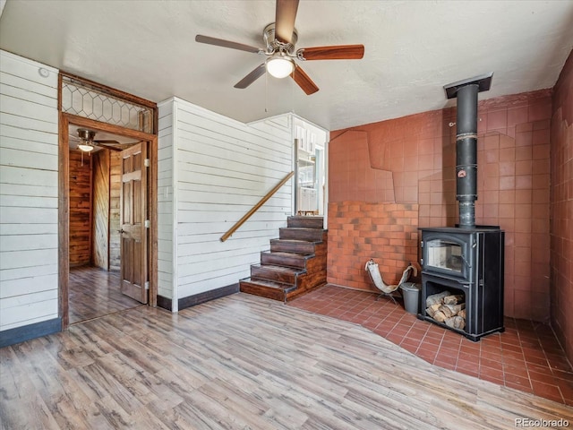 366 Houston St, Bailey, CO 80421 - unfurnished living room with ceiling fan, a wood stove, wood finished floors, wood walls, and stairs