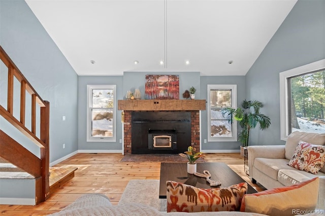 living room featuring a fireplace, high vaulted ceiling, light hardwood / wood-style flooring, and plenty of natural light