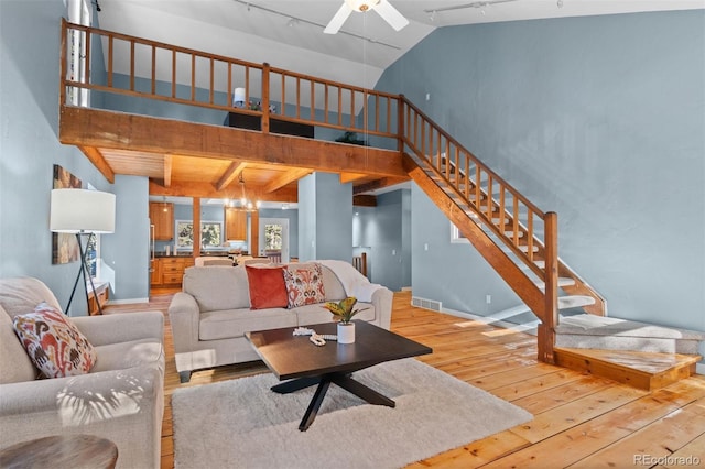 living room featuring ceiling fan with notable chandelier, beam ceiling, light wood-type flooring, and high vaulted ceiling