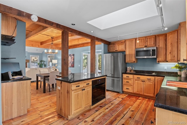 kitchen with light wood-type flooring, black appliances, decorative light fixtures, beamed ceiling, and a center island