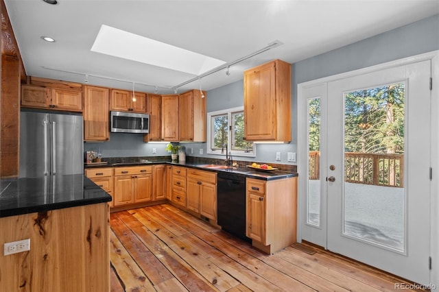 kitchen featuring a skylight, track lighting, sink, black appliances, and light hardwood / wood-style flooring