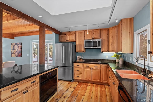 kitchen with black appliances, rail lighting, sink, light hardwood / wood-style flooring, and beamed ceiling