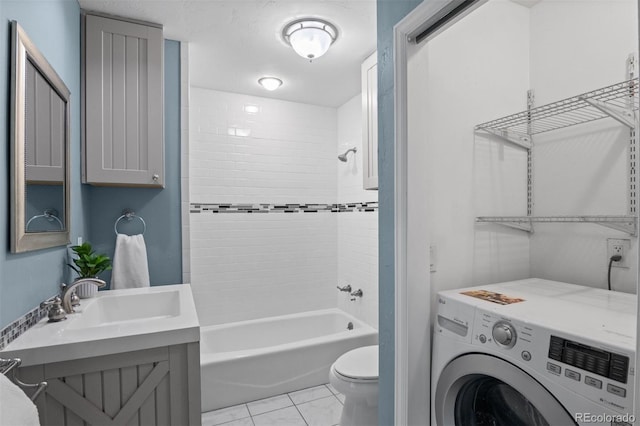 full bathroom featuring tile patterned floors, vanity, tiled shower / bath combo, washer / clothes dryer, and toilet