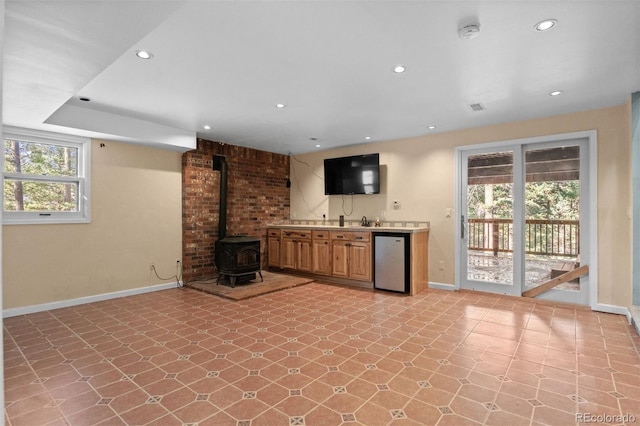 interior space with a wood stove, a wealth of natural light, and stainless steel dishwasher