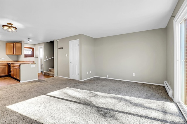 unfurnished living room featuring light carpet and baseboard heating