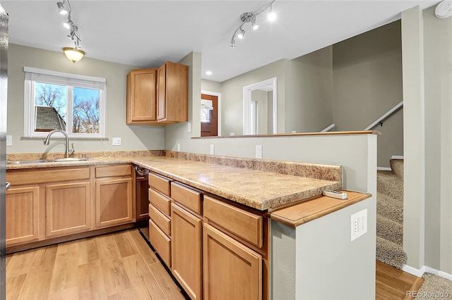 kitchen with kitchen peninsula, sink, and light wood-type flooring