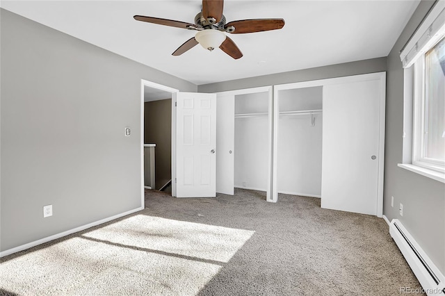 unfurnished bedroom featuring ceiling fan, a baseboard radiator, multiple closets, and carpet