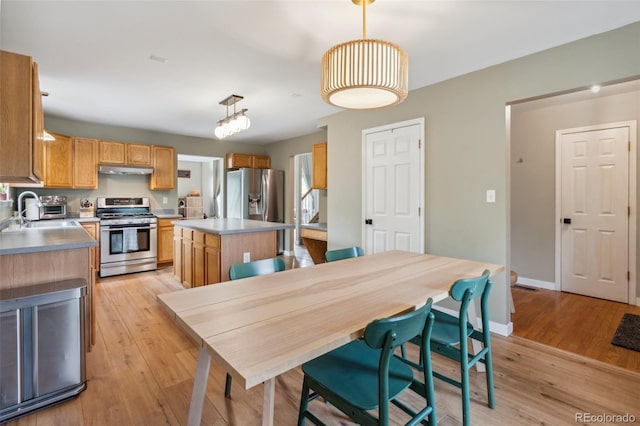 133 Wheat Ridge St, Palmer Lake, CO 80133 - kitchen with stainless steel appliances, light wood-style flooring, a kitchen island, and under cabinet range hood